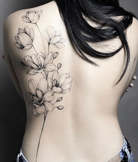 the back of a woman's body with flowers tattooed on her upper and lower back