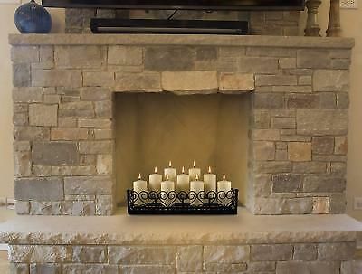 a fireplace with candles lit in front of a flat screen tv mounted on a stone wall