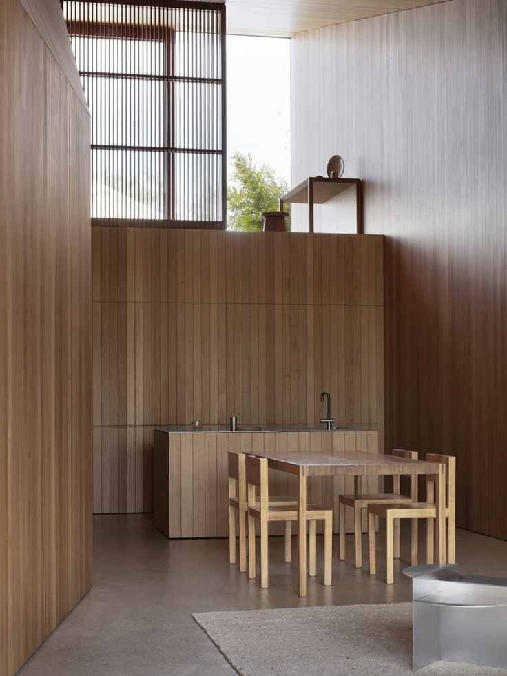 a kitchen with wooden walls and flooring next to a dining table in front of a window