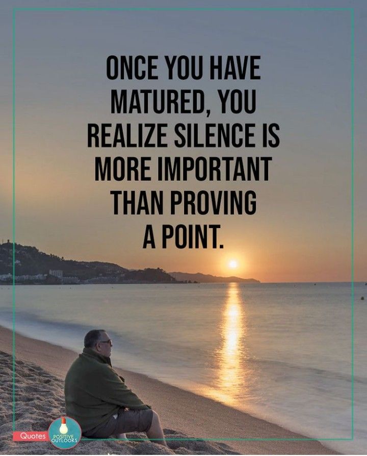 a man sitting on top of a beach next to the ocean with a sunset in the background