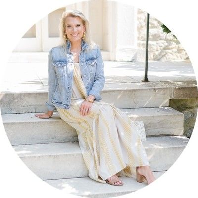 a woman sitting on the steps in front of a building wearing a dress and denim jacket