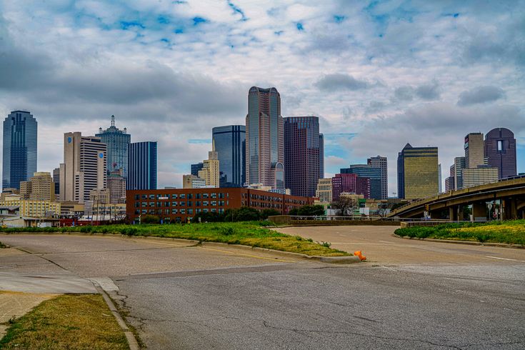 an empty parking lot in front of a large city with tall buildings on the other side