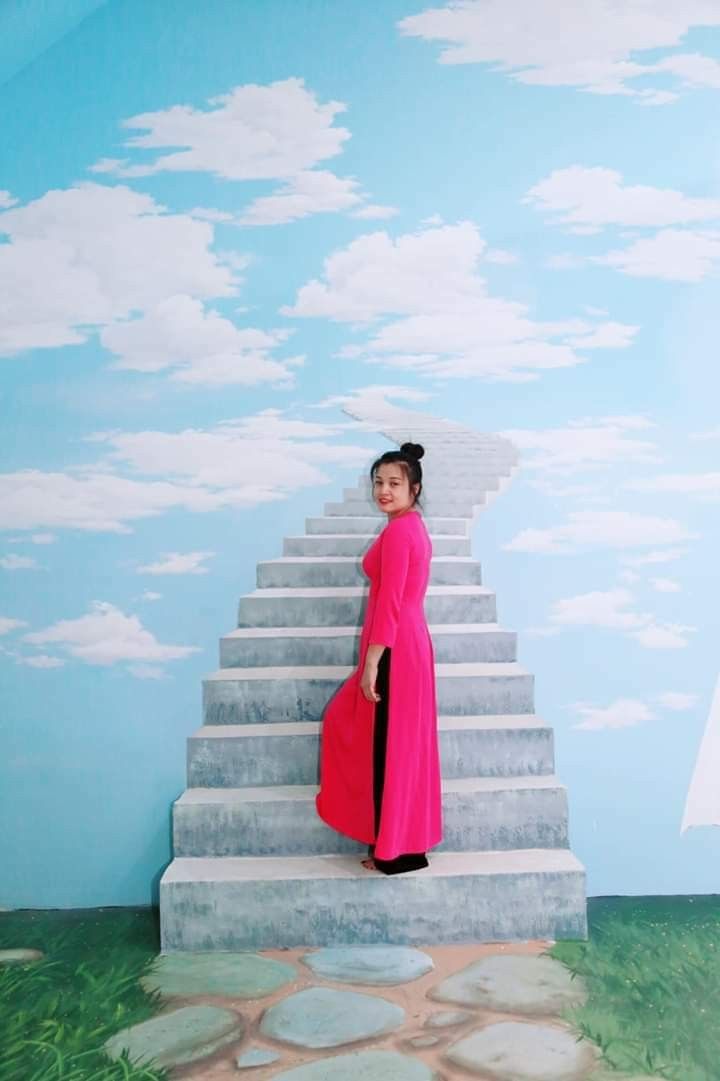 a woman in a pink dress standing on the steps to a sky painted wall behind her