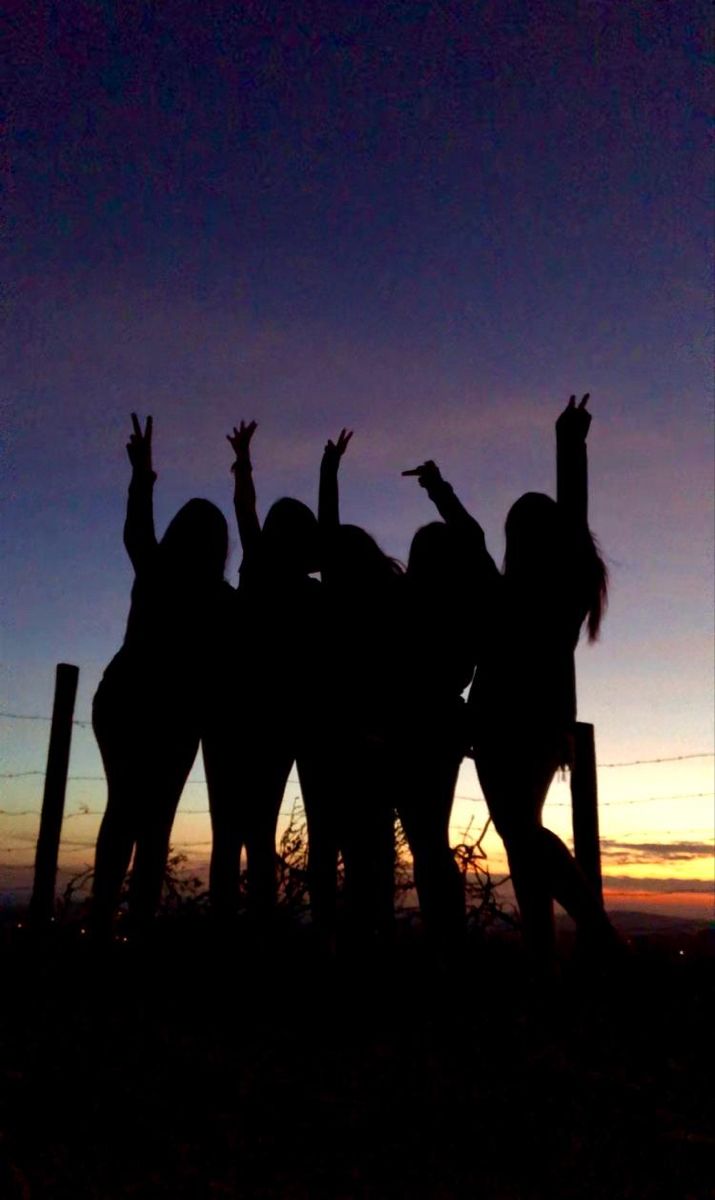 silhouettes of people reaching up in the air with their arms raised at sunset or dawn