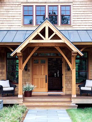 a wooden house with two chairs on the front porch