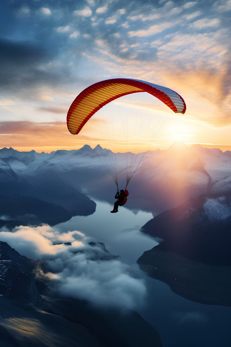 a person paragliding over the mountains at sunset