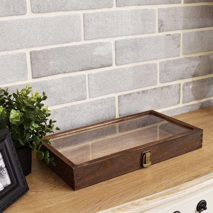 a wooden box sitting on top of a counter next to a potted green plant