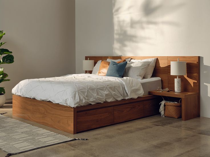 a bed sitting in the middle of a room next to a lamp and a potted plant