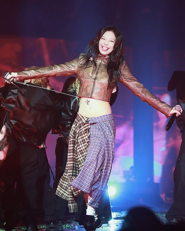 a woman is dancing on stage in plaid pants