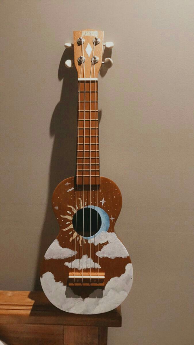 a wooden ukulele sitting on top of a table next to a brown wall