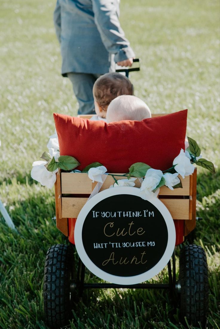 two children are riding in a wagon on the grass