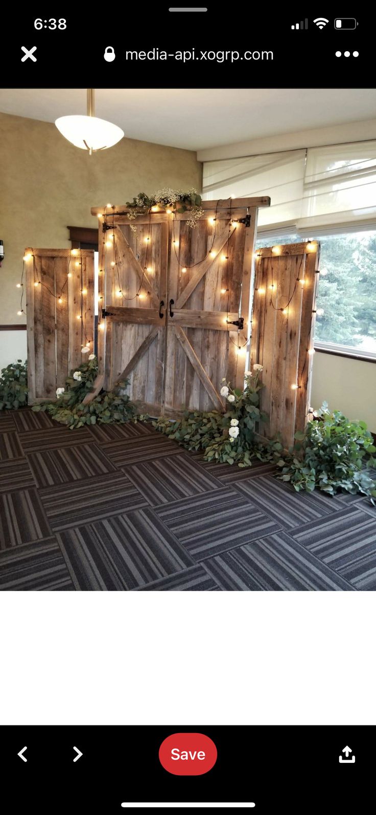 an image of a room decorated with lights and greenery on the floor, as well as a barn door