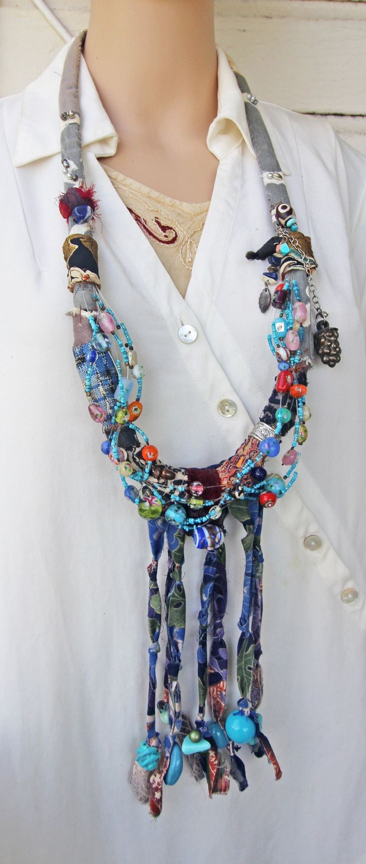 a woman wearing a white shirt and multicolored beaded necklace on top of a mannequin