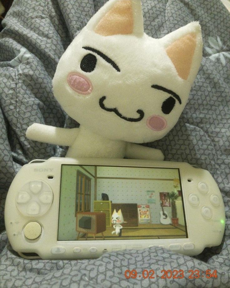 a stuffed animal sitting on top of a nintendo wii game controller with an image of a cat on the screen