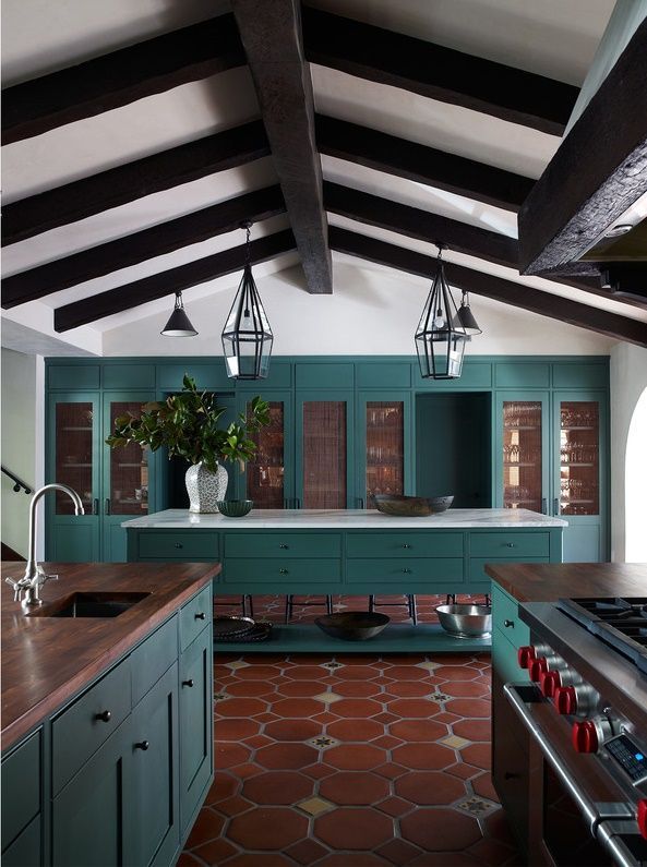 a kitchen with green cabinets and an island in the middle is decorated with red tiles