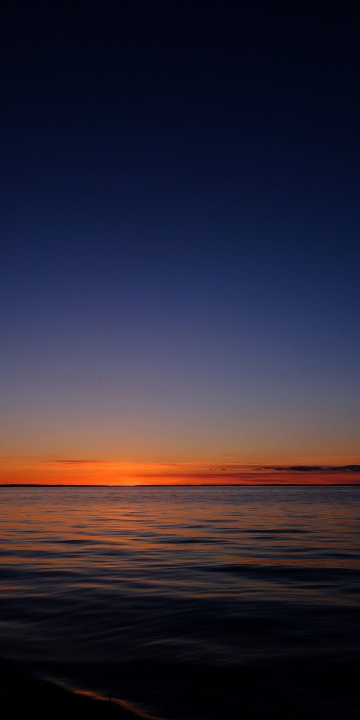 the sun is setting over the ocean with calm water