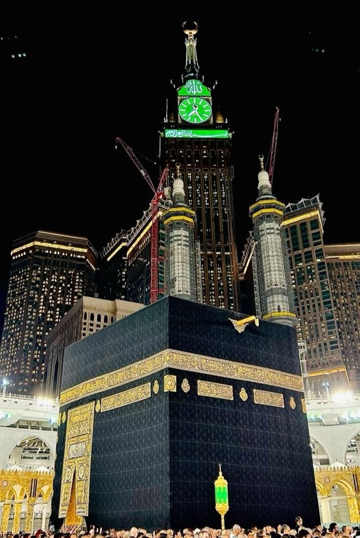 the ka'bah in front of some tall buildings with a clock on top