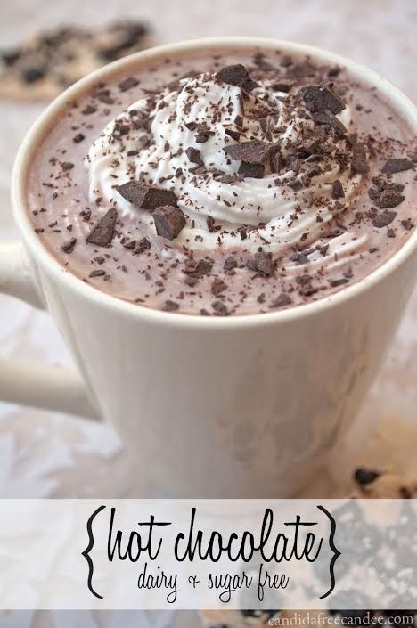 a cup of hot chocolate with whipped cream and chocolate chips on the rim, sitting on a table