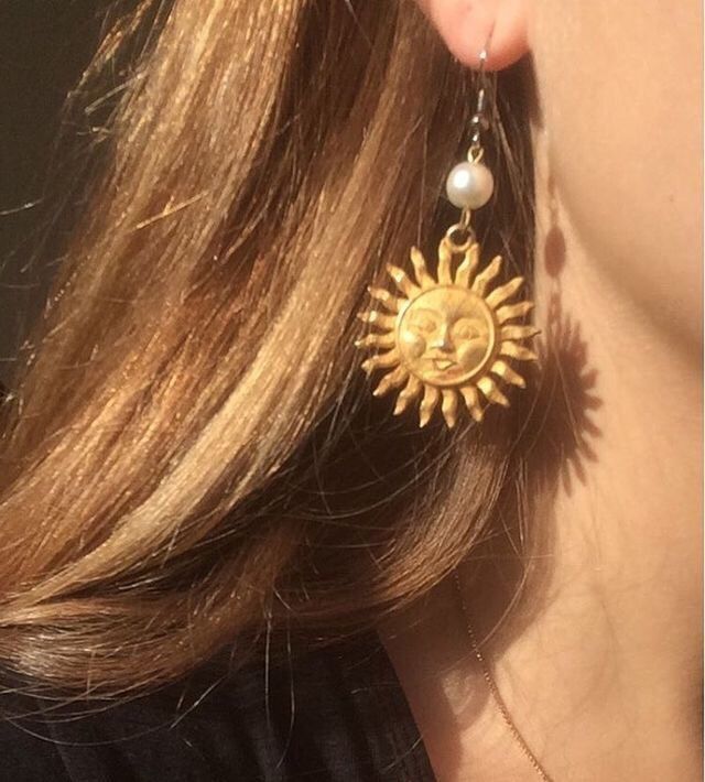 a close up of a person wearing earrings with sun and moon designs on it's ear