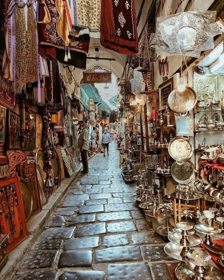 an alley way with lots of items hanging from the ceiling and people walking down it