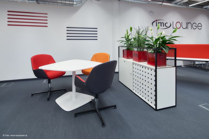 an office cubicle with two chairs and a table in the middle, next to a planter