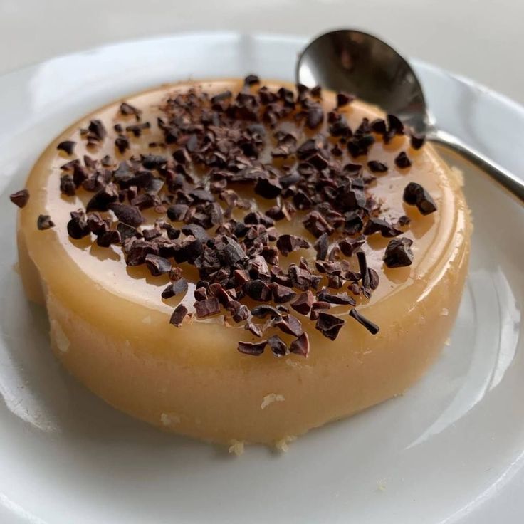 a dessert on a white plate with a spoon in the middle and chocolate sprinkles all over it