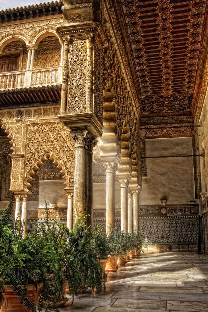 an intricately decorated building with potted plants in the foreground and columns on either side