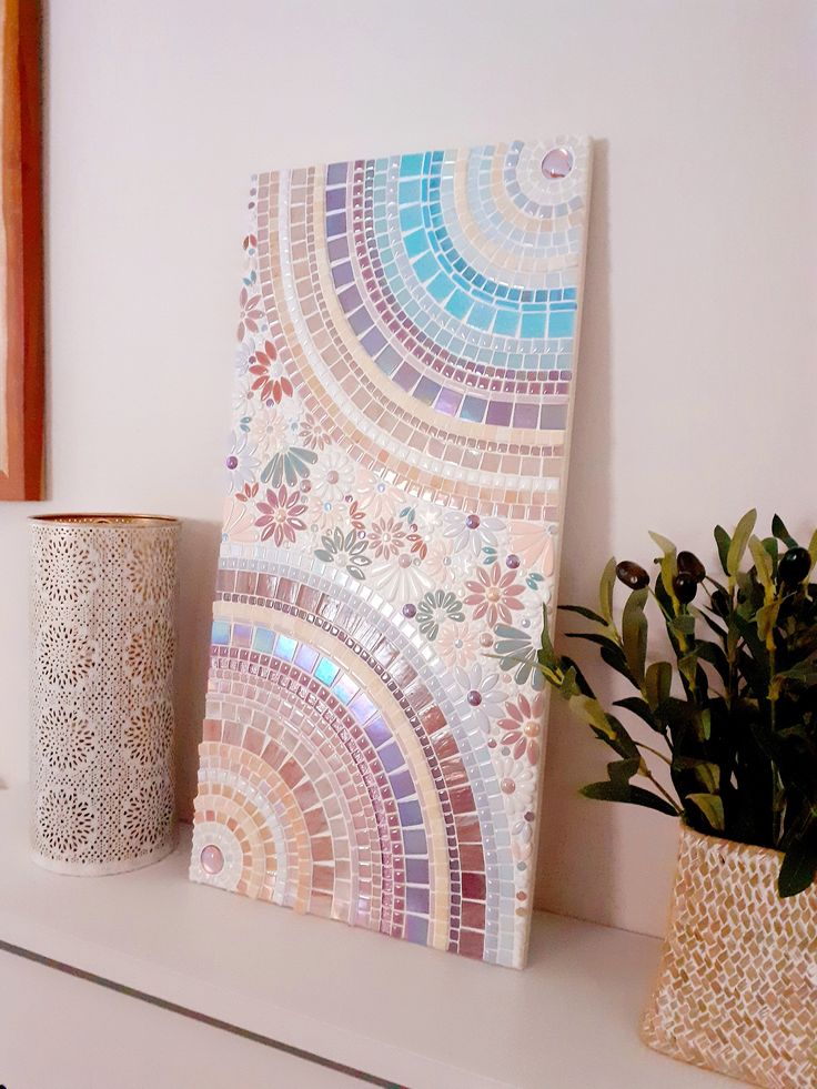 a painting and vase on a shelf next to a potted plant in front of it