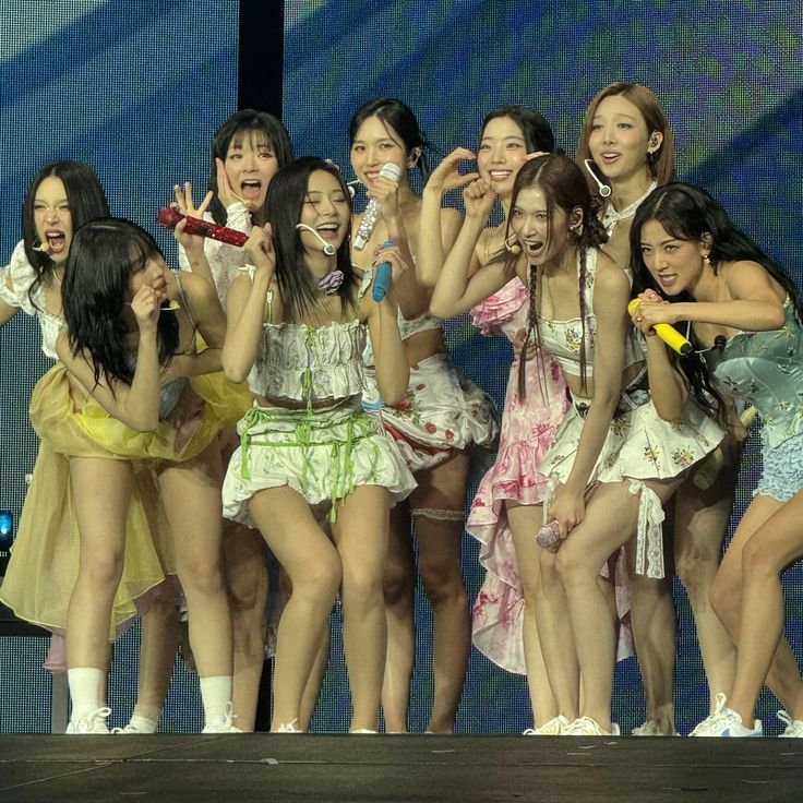 a group of young women standing on top of a stage with their hands in the air