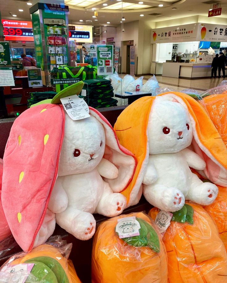 two stuffed animals sitting next to each other in front of orange bags with carrots on them