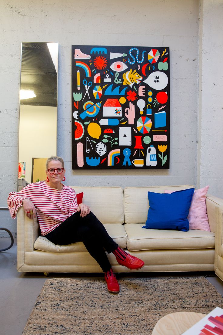 an older woman sitting on a couch in front of a painting