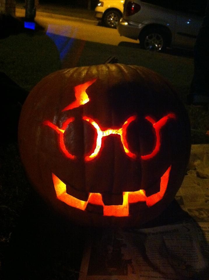 a pumpkin with glasses carved into it's face and glowing eyes on the outside