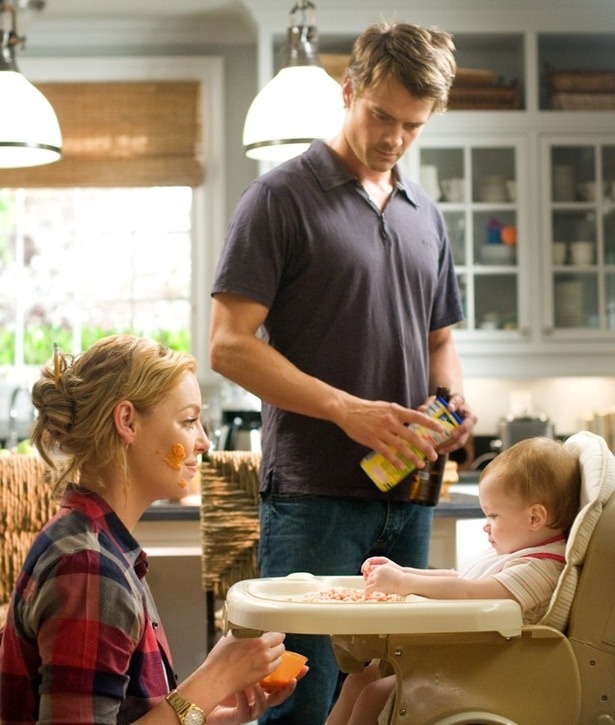 a man standing next to a baby in a highchair with food on it