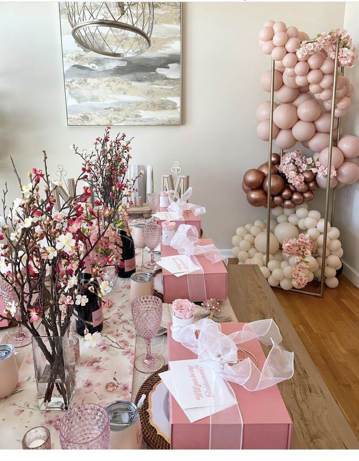 the table is decorated with pink and white flowers, balloons, and gift wrapped presents