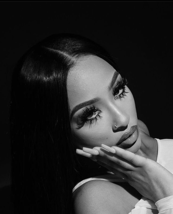 a black and white photo of a woman with long hair holding her hand to her face