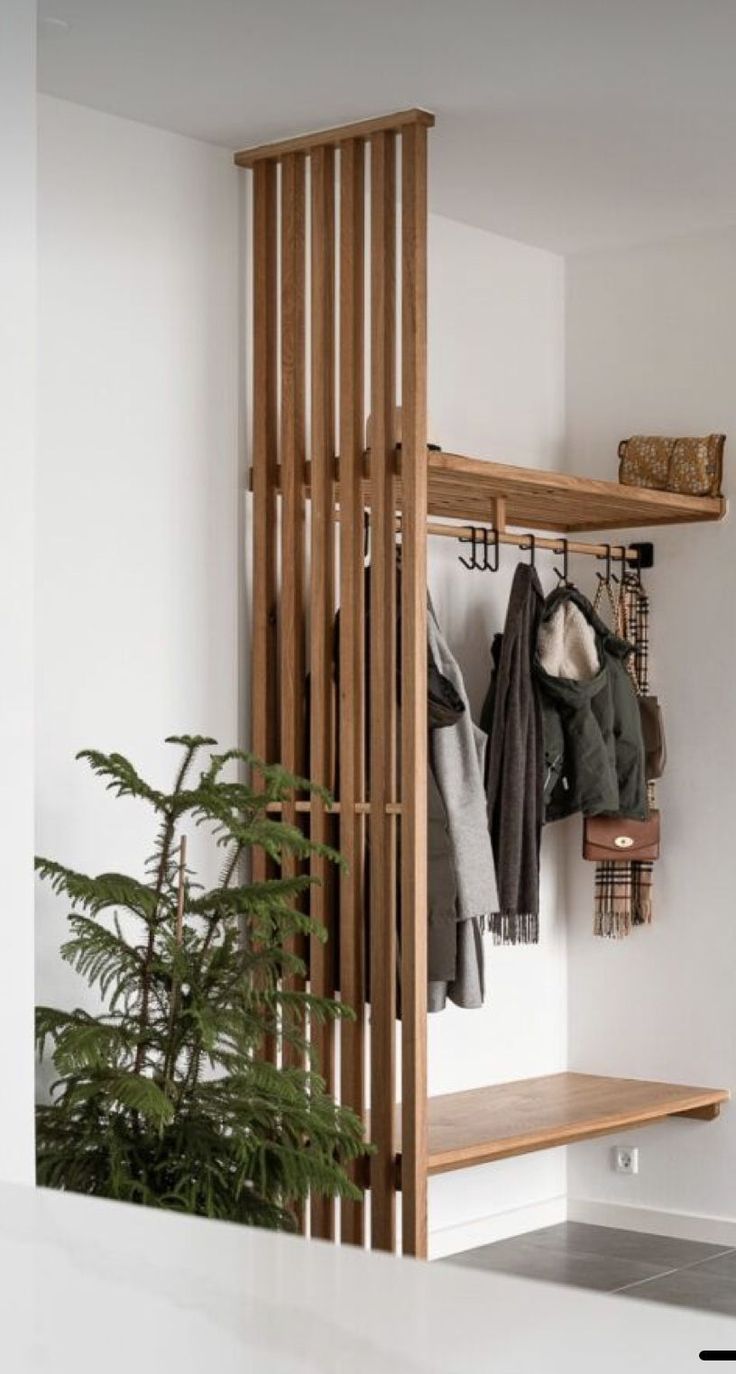 a coat rack with clothes hanging on it and a potted plant next to it