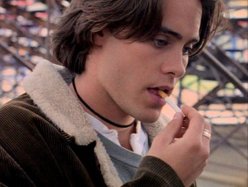 a young man is eating something while standing outside