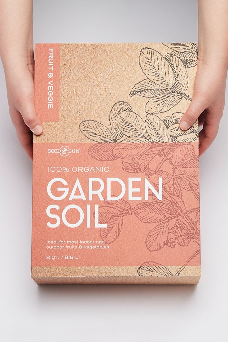 a person holding a box with an organic garden soil packet in it's hands