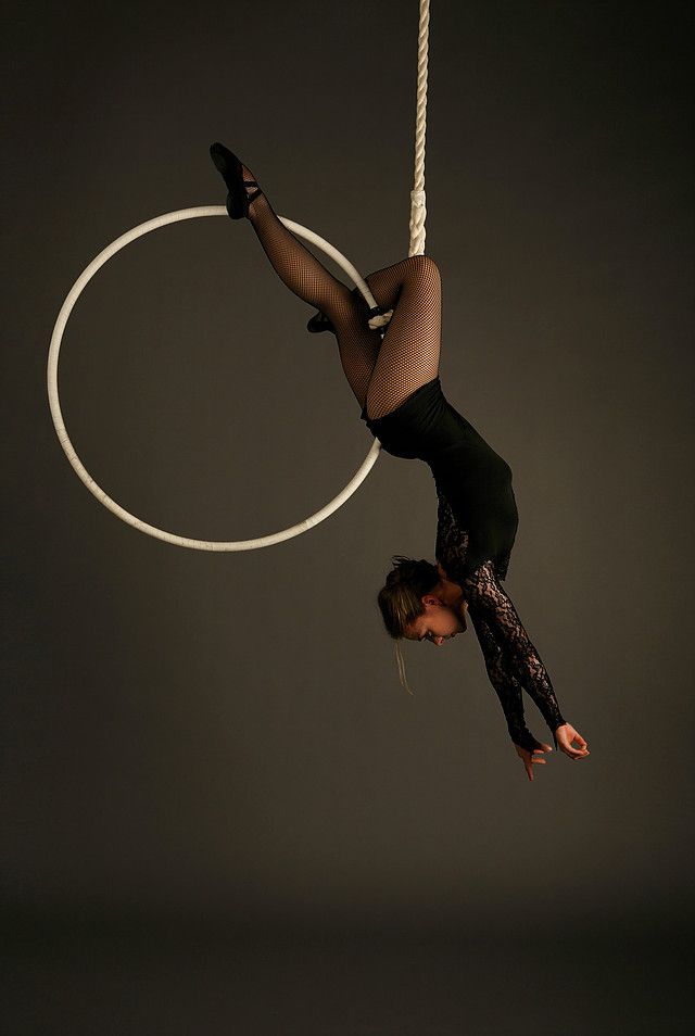 a woman is doing aerial acrobatic tricks on a rope with a hoop