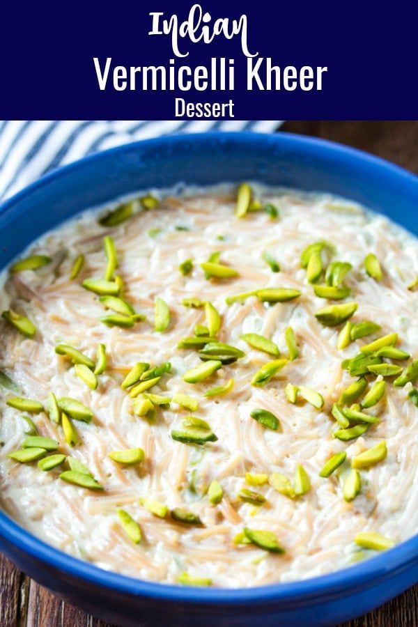 a blue bowl filled with rice and topped with pistachio seeds, on top of a wooden table