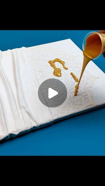 someone is pouring gold paint onto a piece of paper