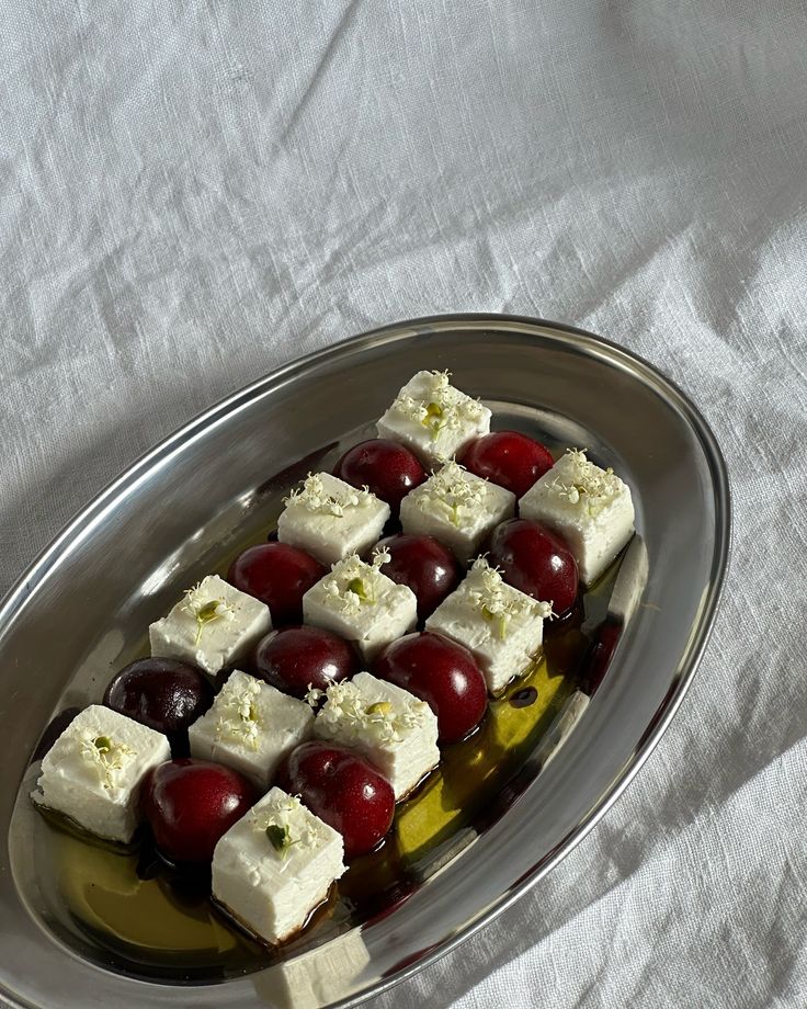 grapes and cheese are arranged on a silver platter with olives in the middle