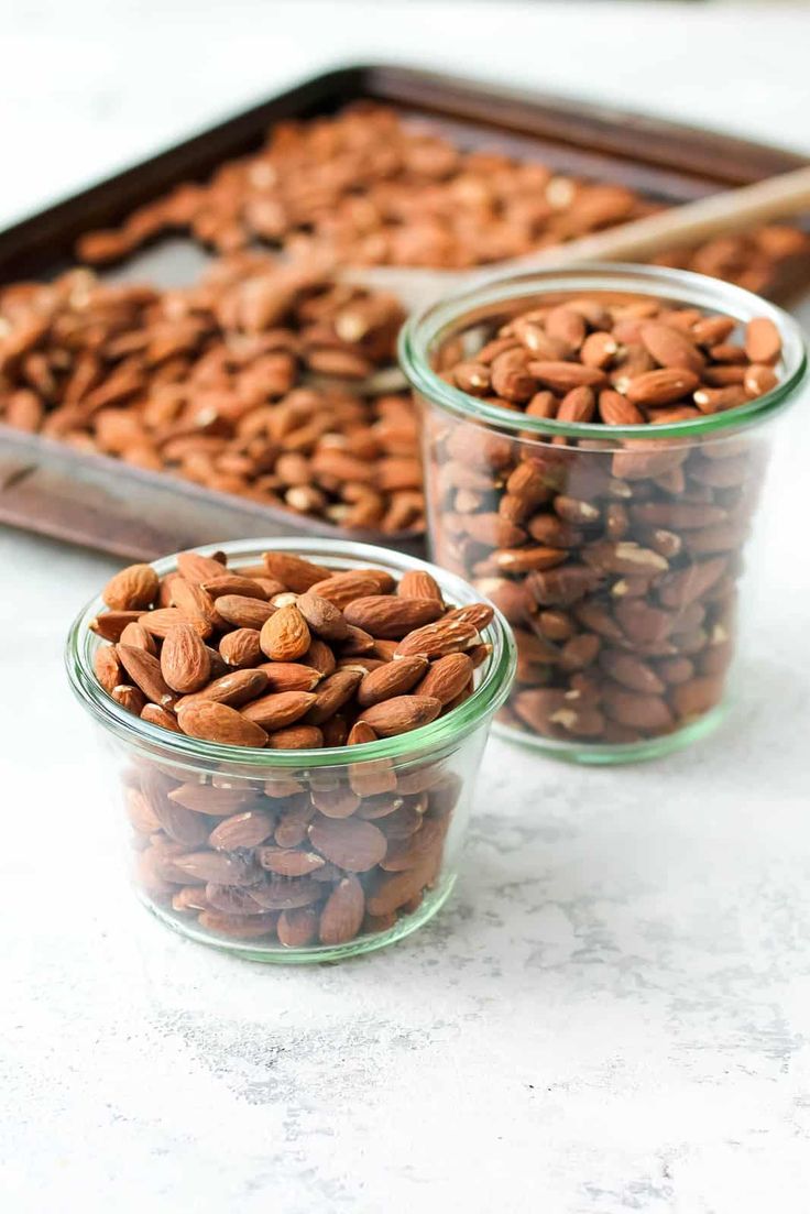 three glass containers filled with nuts on top of a table