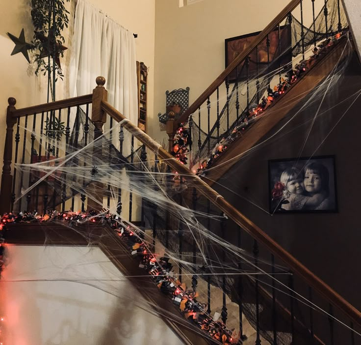 a staircase decorated for halloween with lights and spider webs on the handrailes