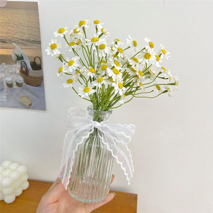 a person holding a vase with daisies in it