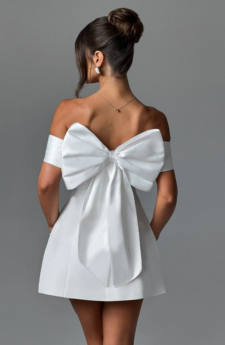 the back of a woman's white dress with a large bow at the waist