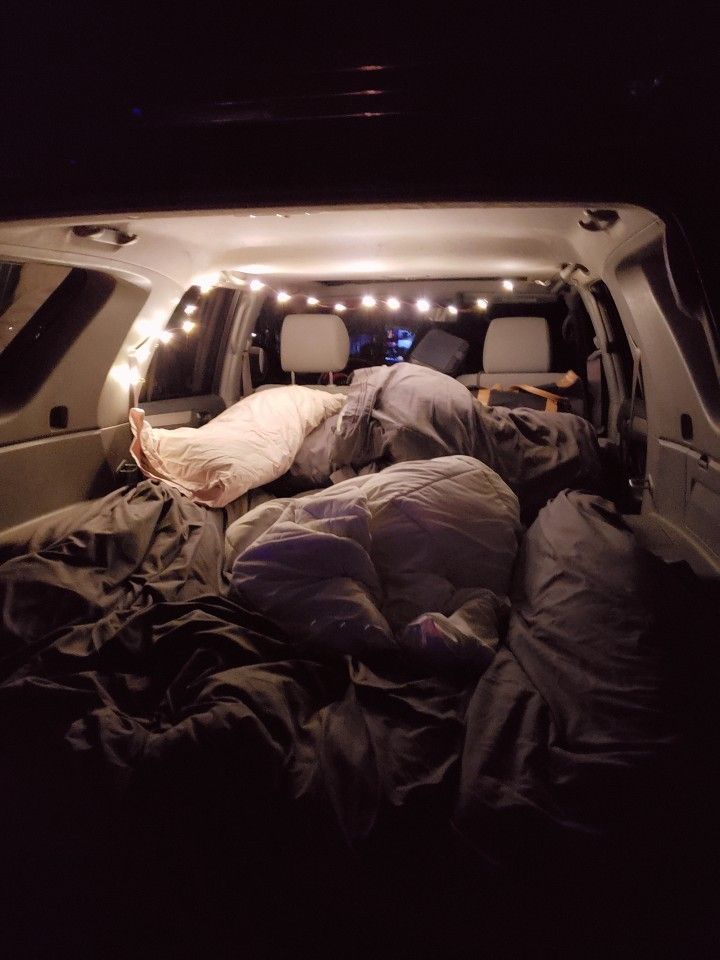 the inside of a van with an unmade bed and lights on it's sides