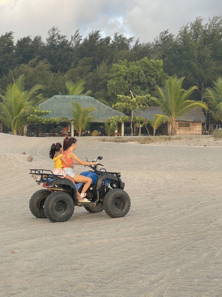 two people riding an atv on the beach