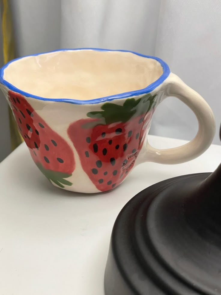 a ceramic cup with strawberries painted on it