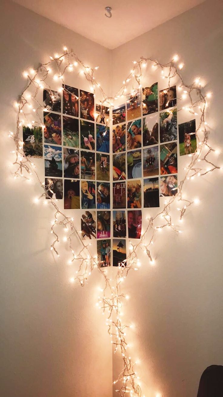 a heart shaped photo collage with lights hanging from the wall and pictures on it